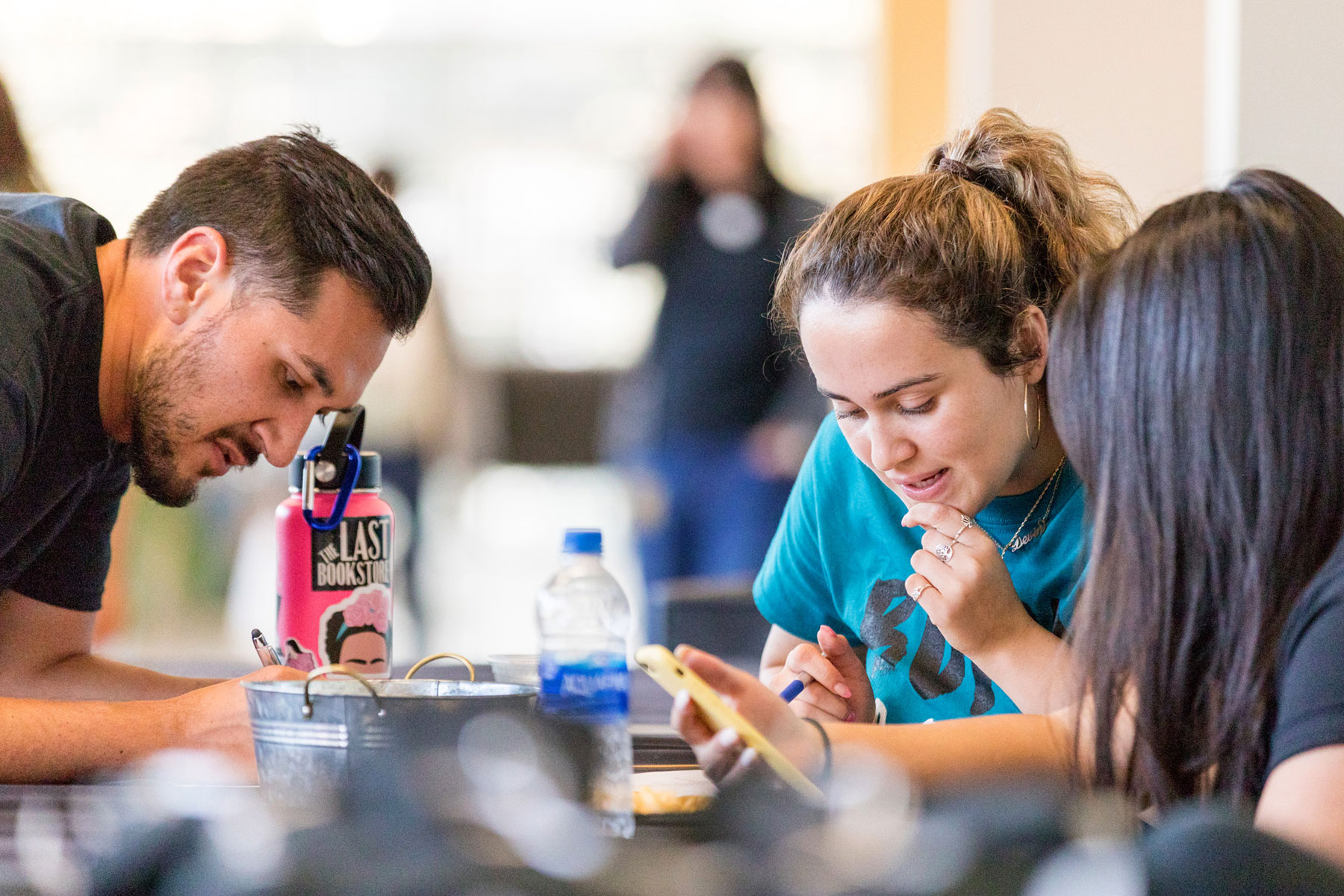 Three students looking at items on a table. 