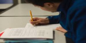 student taking notes with pencil and notebook