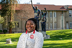 Black female in white blouse in front of Victory statue at SJSU