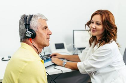 Audiologist conducts hearing screening on patient