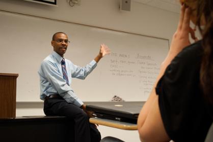 Instructor gestures towards a white board