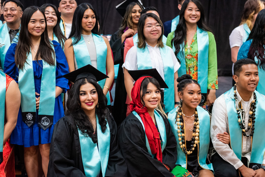 API student graduates pose with their teal stoles.