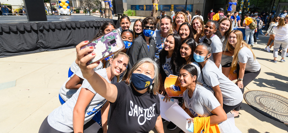 A staff member take a photo with students for social media.