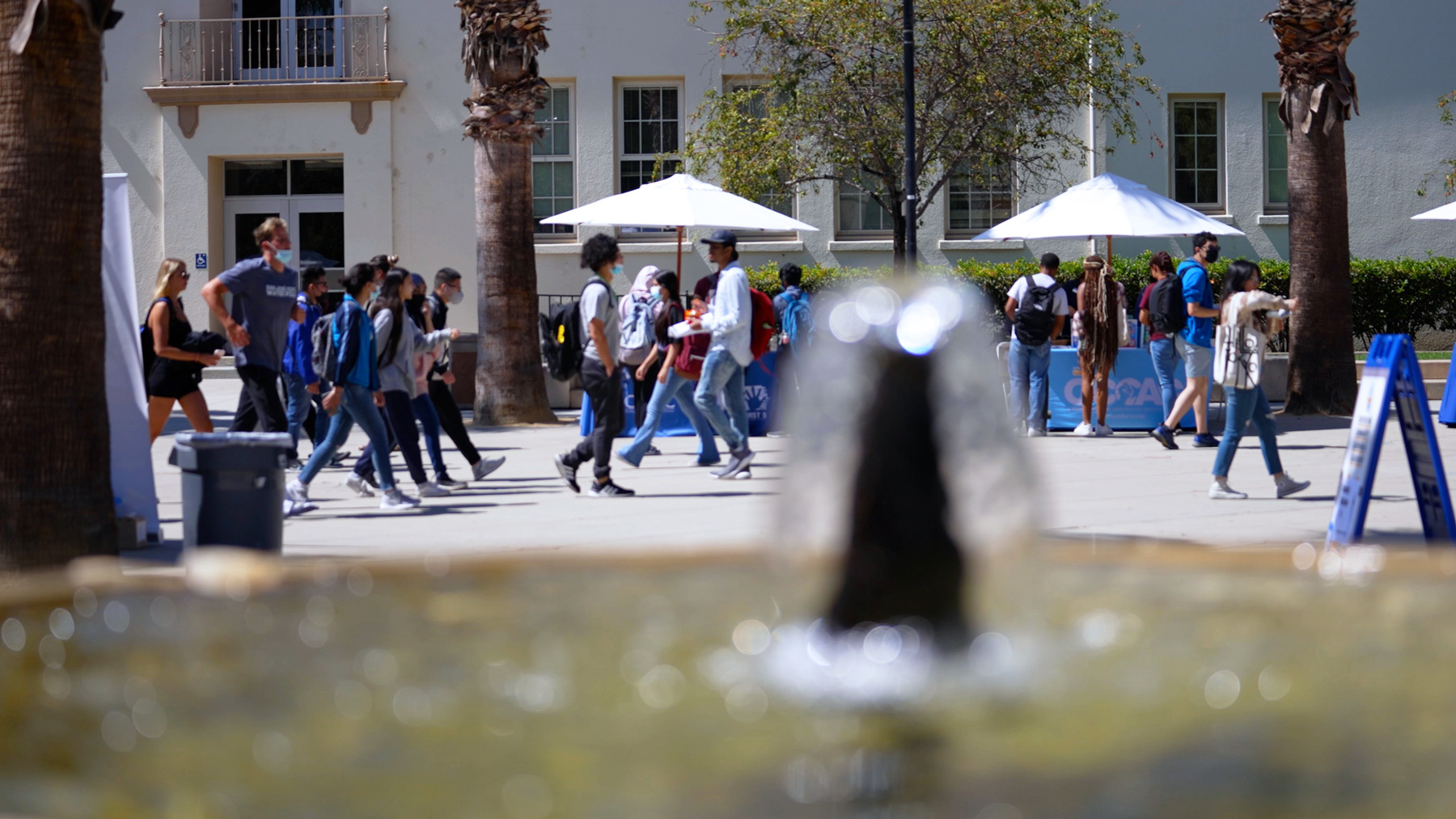 Students walking through the Paseo with a water fountain on the foreground.