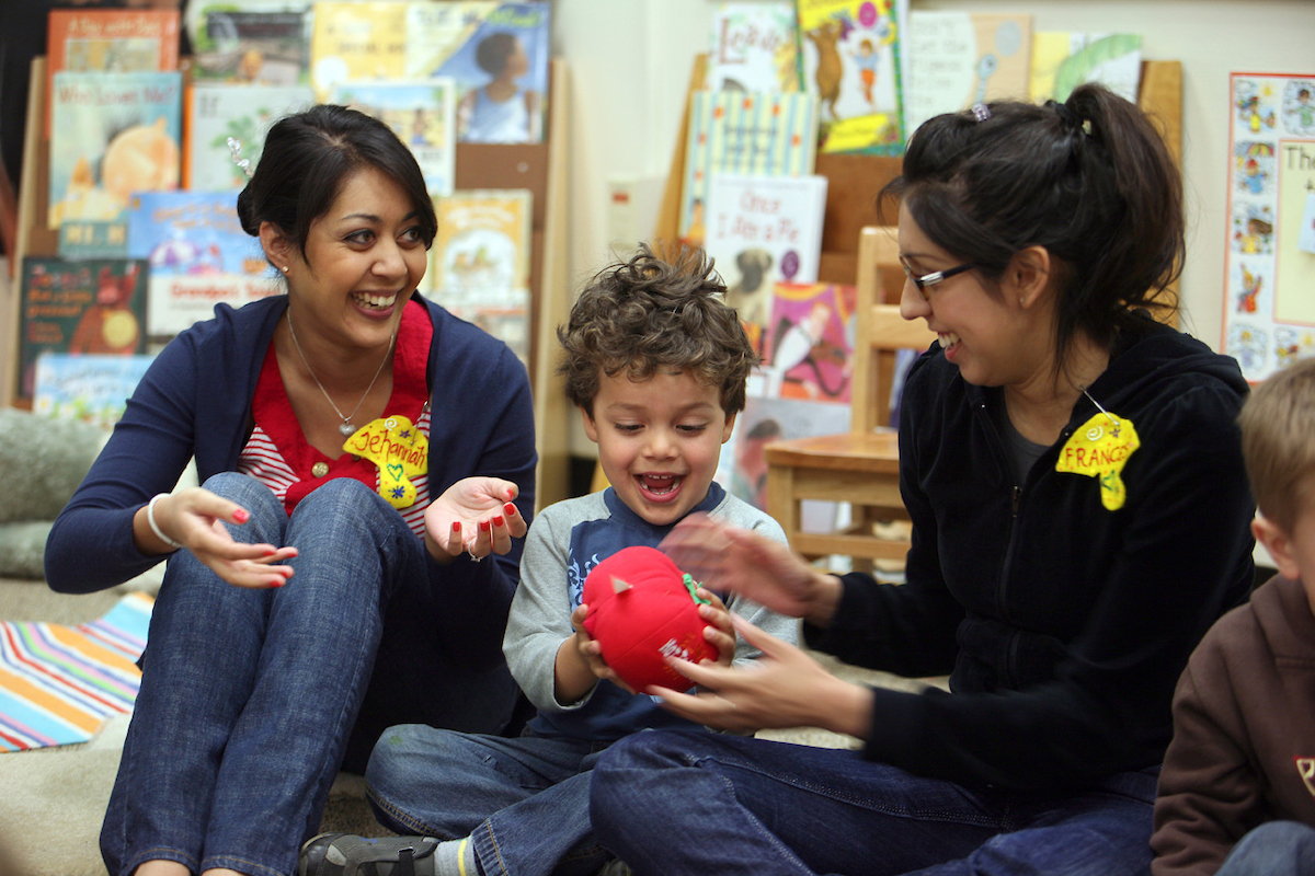 Two students work with a child in a classroom.