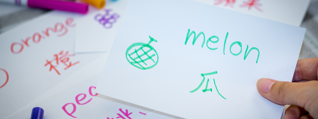 in the foreground a white index card with green wrting being held by a hand in front of other cards and markers.