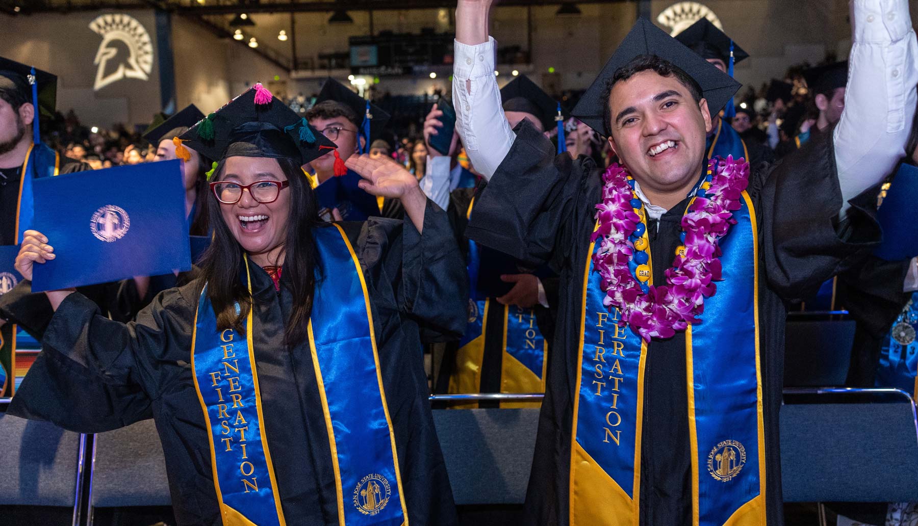 Two graduates pose with their diploma during commencement.