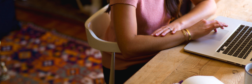 Woman in pink shirt using trackpad on her laptop.