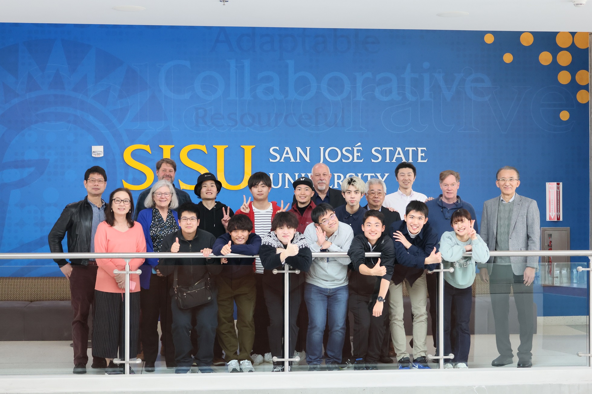 A group of people standing in front of a San José State University sign