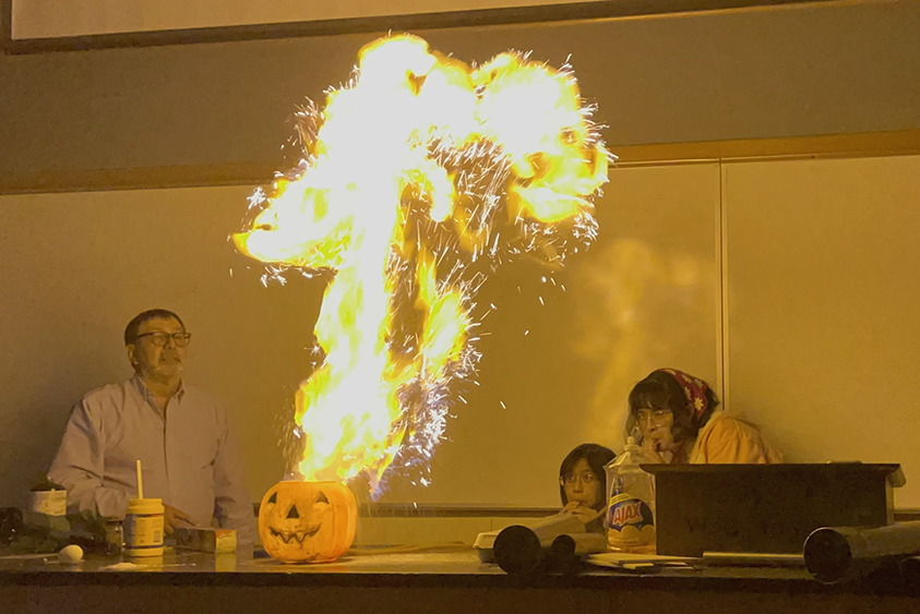 Photograph of Alejandro Garcia and students with a fireball of corn starch.