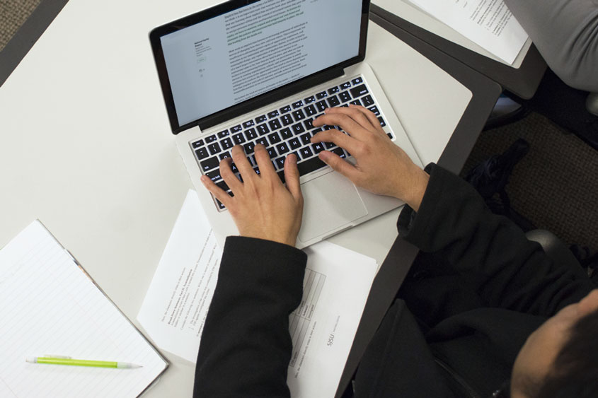 Student reading an article on his laptop while studying.