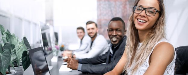 Four people working on laptops smile at the camera