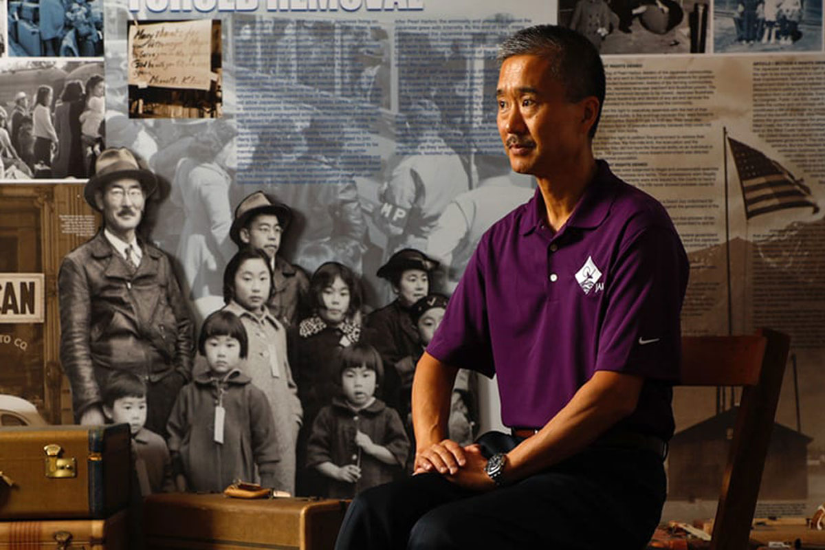 Michael Sera posing in front of a collage about Japanese history.