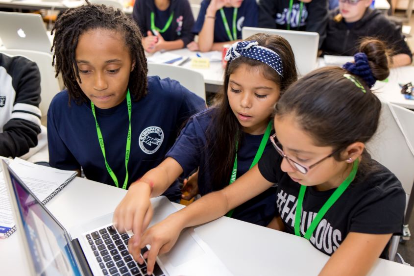 Three young girls sitting in front of a laptop.