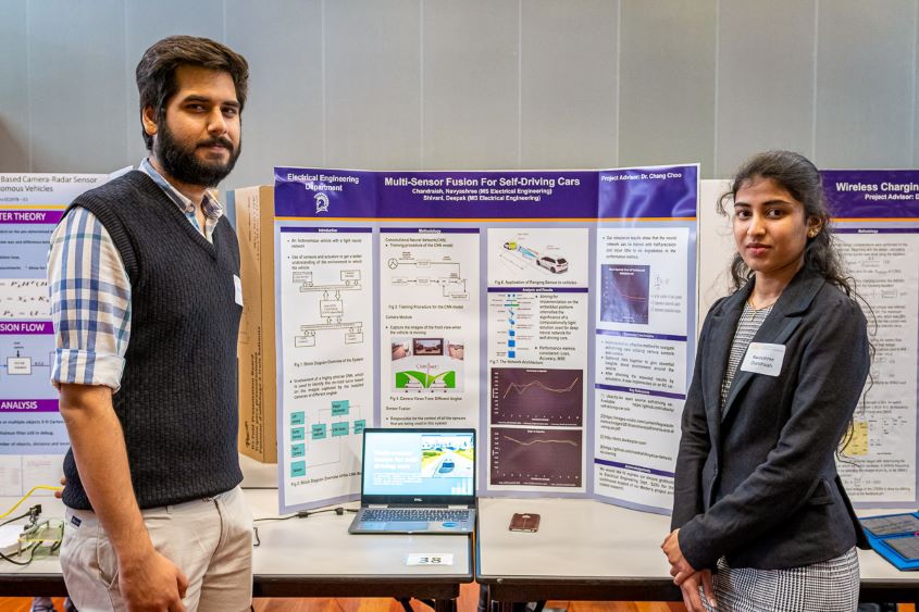 Two students standing in front of their poster.