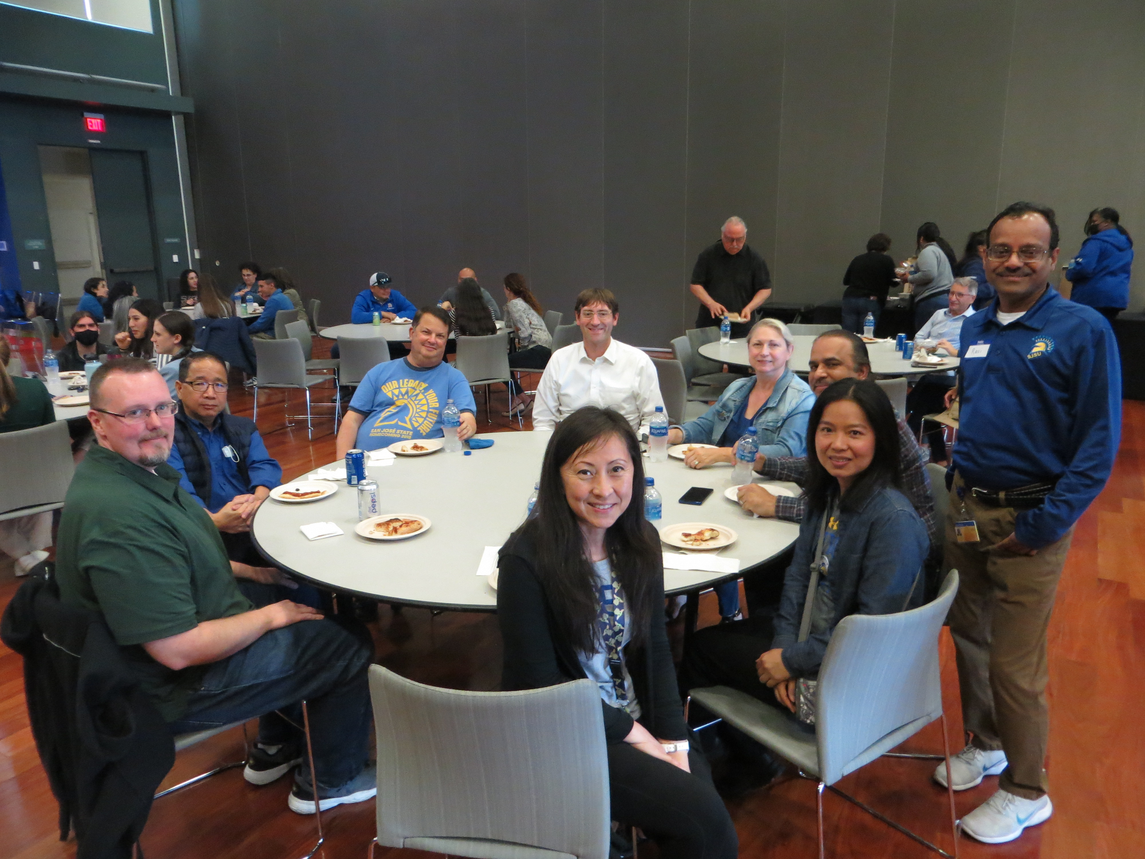 Staff seated at a round table and posing for a photo