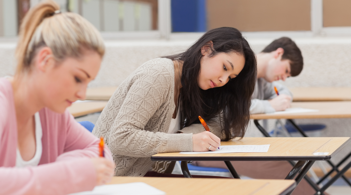 Three students in the classroom taking an exam.