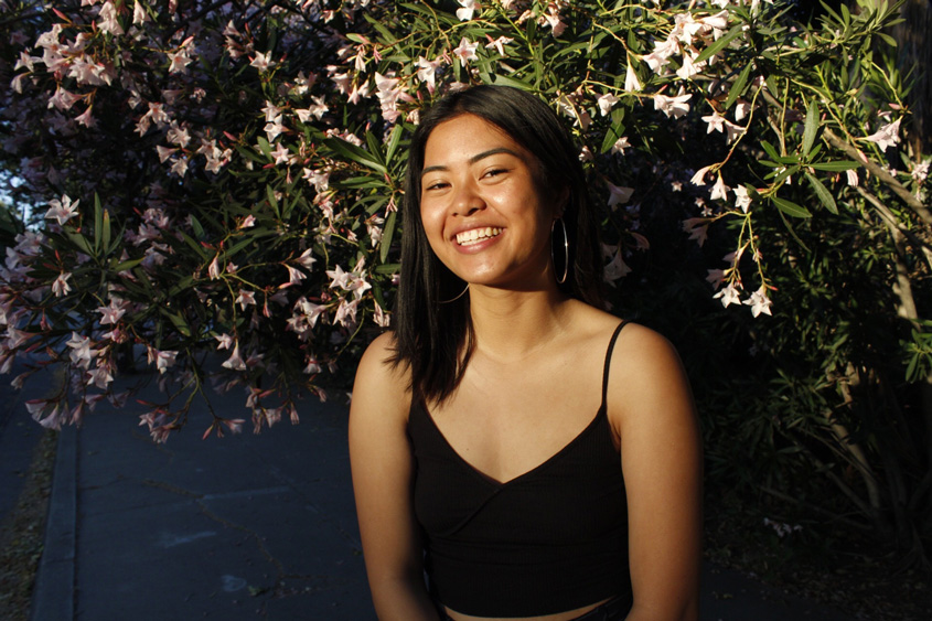 Marielle Lacanlale posing in front of a flower wall.